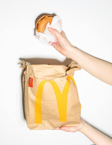 Photo d'un hamburger tenu au dessus d'un sac Mcdonald's